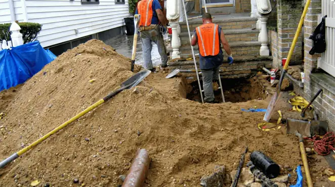 Contractors performing foundation protection and exterior drainage excavation near residential home steps in Akron, OH